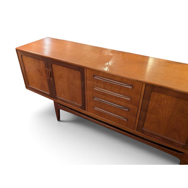 Mid Century Modern credenza in teak, by E. Gomme Limited. Note, holes have been cut in the back for media cords. One chip...