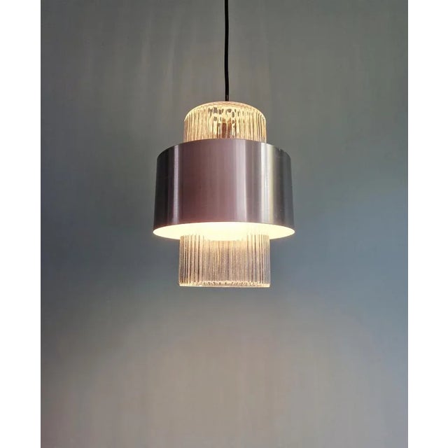 Scandinavian pendant light in grooved clear glass and silver-brushed aluminum, 1960s. The pendant light has been...