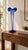 A sculptural glass vase featuring a slender, tapered silhouette and a dramatically flared, ruffled opening. Dark blue...