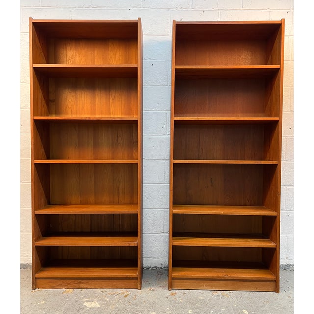 This pair of mid-century modern Danish teak tall bookcases features a warm golden-brown wood grain and multiple adjustable...