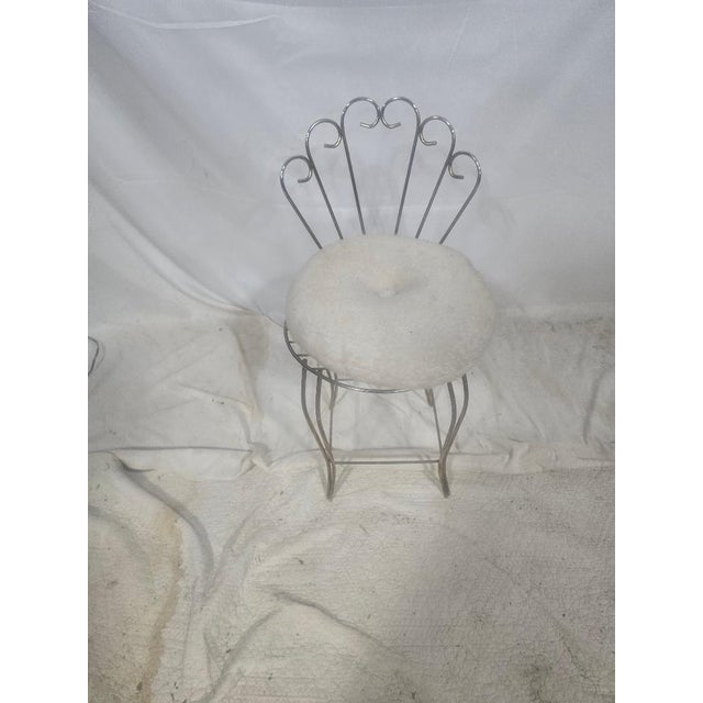 Elegant vintage Hollywood Regency vanity chair featuring a sculptural gold-tone metal frame with decorative fan-back...