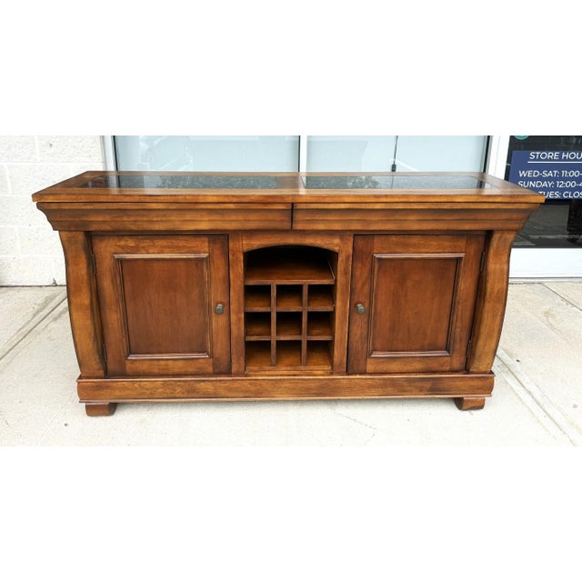 This traditional wood buffet pairs a warm, richly grained finish with two dark stone-inset panels across the top for a...