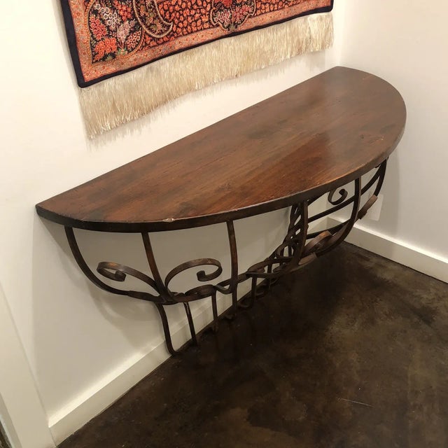 Wall mounted wrought iron console table with a distressed wooden top in a walnut finish. Italy.