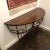 Wall mounted wrought iron console table with a distressed wooden top in a walnut finish. Italy.