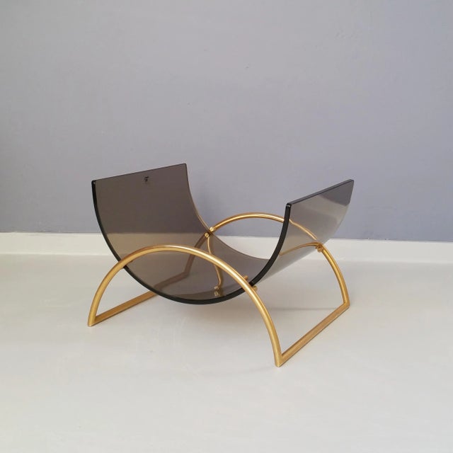 This magazine holder features a brass frame with thick curved smoked glass. This piece has an attribution mark, I am sure...