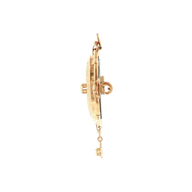 An ornate Victorian 13k gold pendant with intricate floral engravings. Central pearl accent surrounded by a detailed...