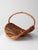 A sculptural vintage wicker kindling basket featuring a dramatic crescent shape and fixed woven handle. The elevated base...