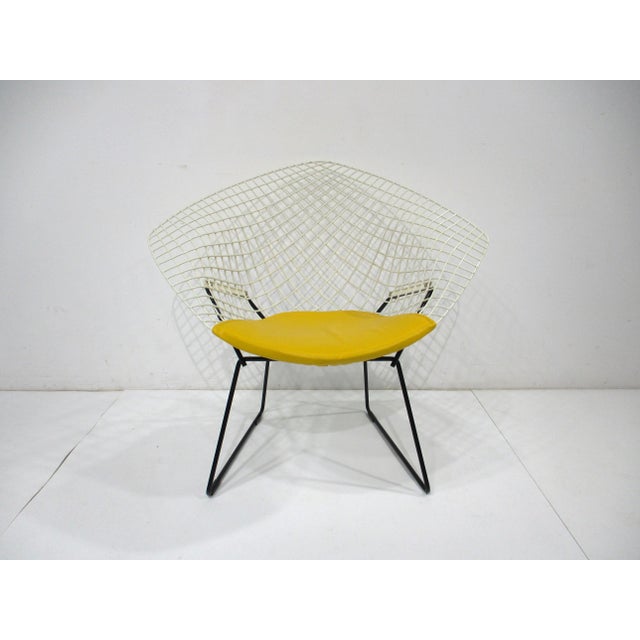 A white coated sculptural welded wire Diamond lounge chair with contrasting satin black steel base and sunflower yellow...