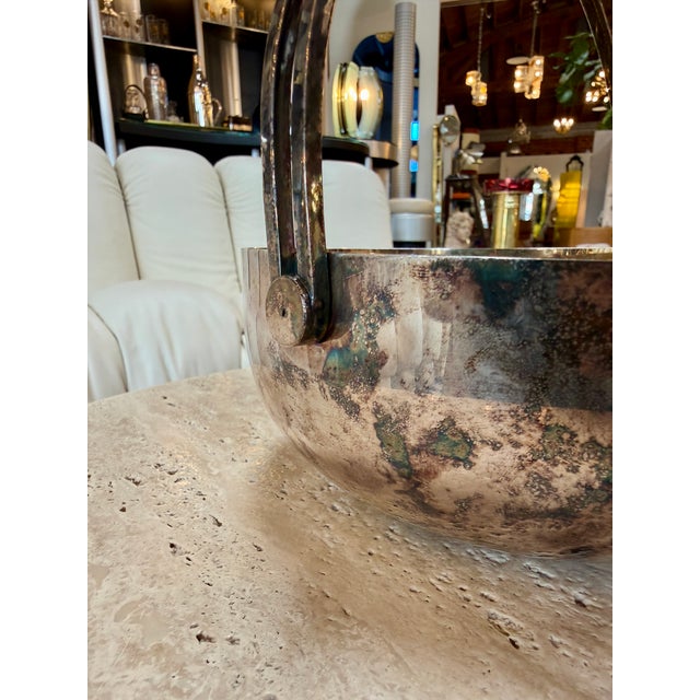 Elegant vintage Italian bowl featuring a silver-plated exterior, warm gilt interior, and sculptural double-arched handle....