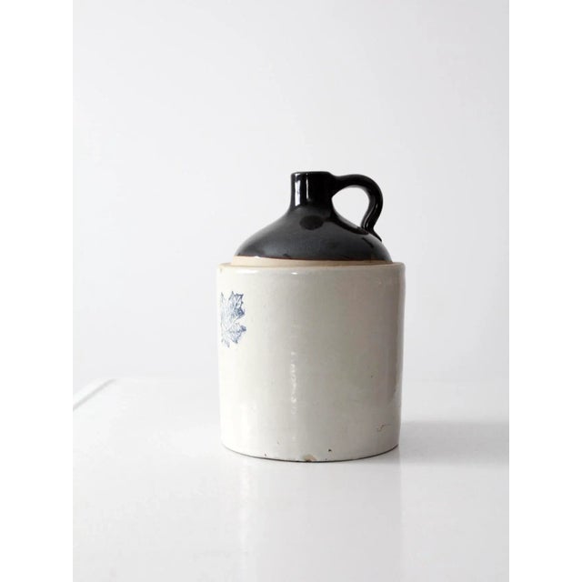 This antique Western Stoneware crock jug features a dark brown slip top over a naturally glazed base. The front is...