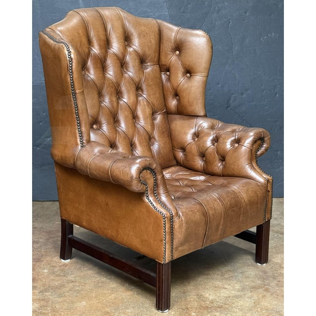 A fine English wingback armchair or library lounge chair - upholstered in tanned leather in the George III style -...