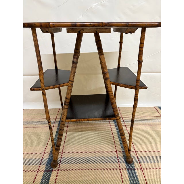 This table is an early 1900s Primitive English Burnt Bamboo multi tier side table. Its crafted from rustic scorched bamboo...