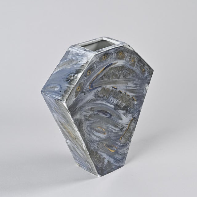 Polygonal slip-cast porcelain vase with painted decoration and gold highlights. Broad, bluish and gray brushstrokes...