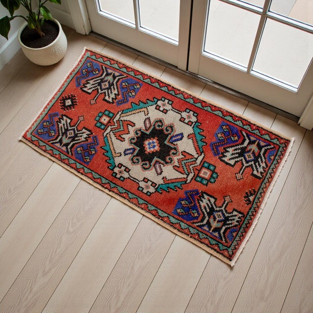 This vintage Oushak mat exudes a warm, rustic charm with its vibrant terracotta field and beautifully aged patina. The...