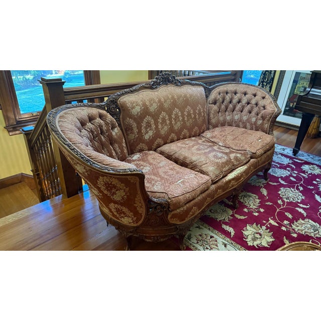 A richly carved Victorian Rococo Revival sofa with dramatic serpentine form and deep tufted barrel-curved arms. The carved...