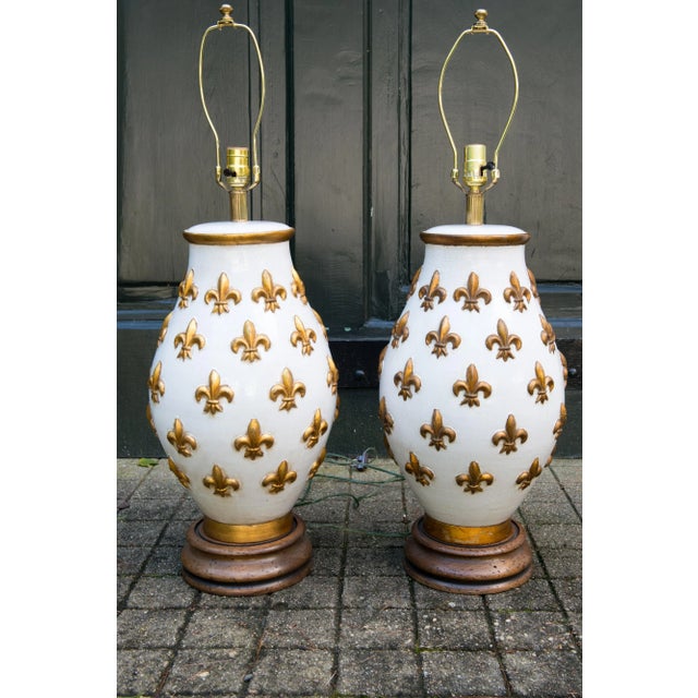 Large spectacular pair of ceramic fleur de lis lamps. White and gold gilt glaze. Wood bases. 26" high to the top of the...