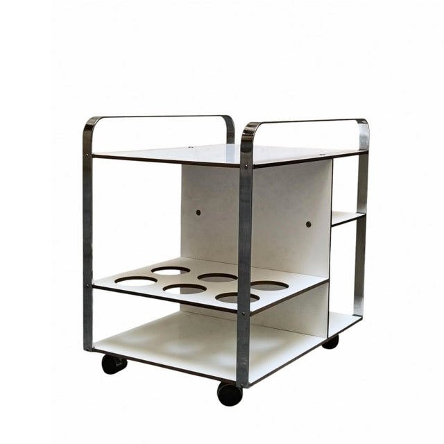A serving trolley from the 1970s, characterised by a polished chrome frame combined with white laminate shelves. The...