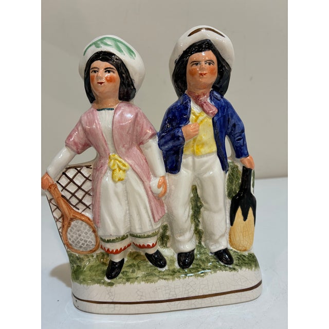 A good original Staffordshire flat back figurines. Cricket Man and tennis woman. The hand painted ceramic figures are in...