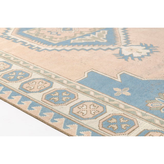 This is a vintage Turkish Oushak rug from the Mid 20th Century. The piece was hand-knotted.