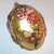 A lovely blown glass large egg shape ornament accented with pastel flowers and a little bumble bee. The ornament is in...