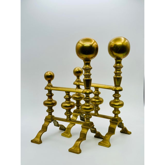 Offering a nicely proportioned set of petite antique fire dogs in warm polished brass.
