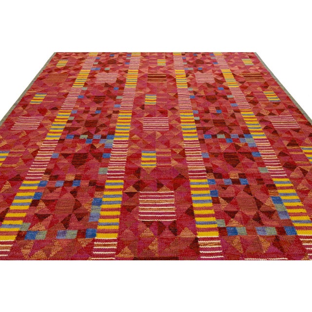 This handknotted flatweave rug draws inspiration from mid-century Swedish "Rölakan" traditions, featuring a rich...