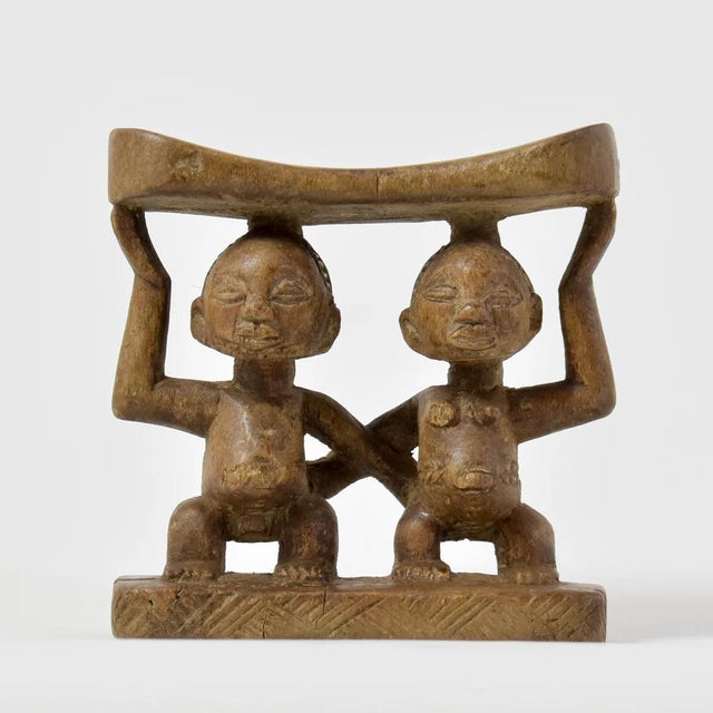The Luba Figural Miniature Headrest from Congo is a finely crafted wooden piece featuring a graceful figure supporting the...