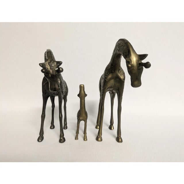 A set of three vintage brass giraffe figurines by Leonard Silver Mfc. Co. The solid brass set includes two larger giraffes...