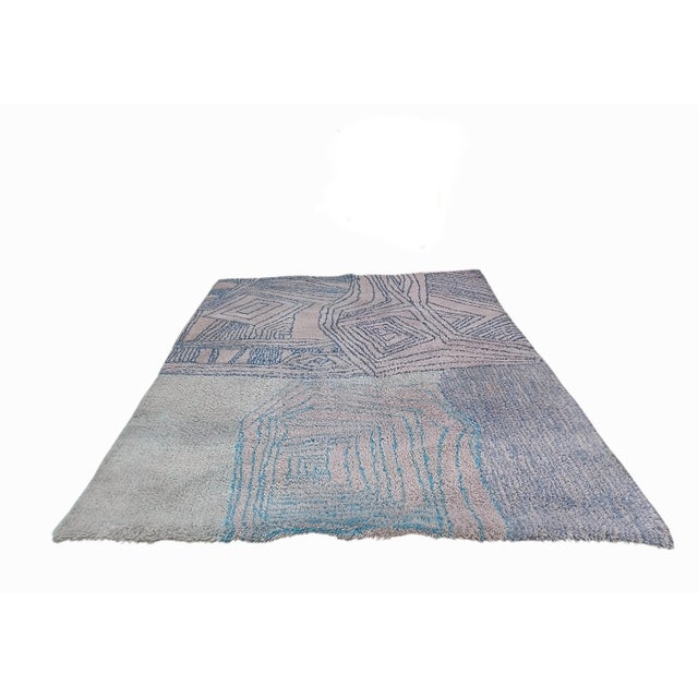 This designer rug stands out for its striking asymmetrical composition. One side features concentric rhombuses and high-...