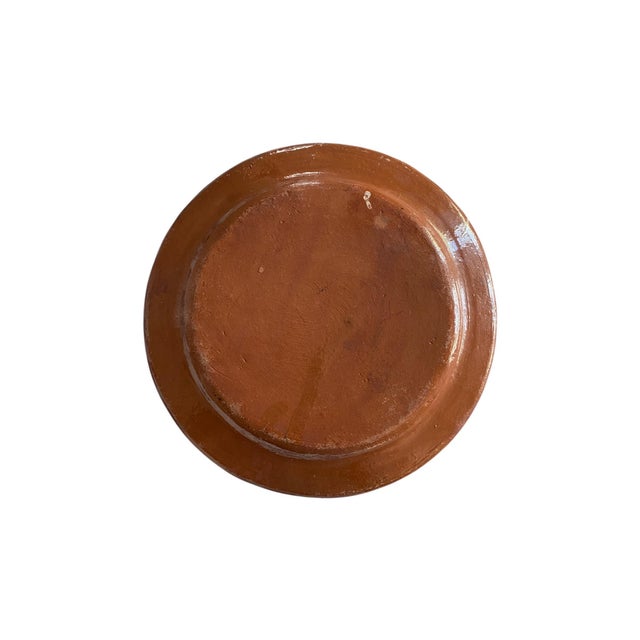 An earthenware decorative plate made in Mexico in the 20th century. The design includes seven daisy-like flowers in creamy...