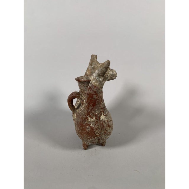 Zoomorphic vase in the form of two-headed deer. Terracotta with a red slip painted with floral motifs. The rounded handle...
