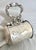 An exquisite retractable razor strap, its leather enclosed in a silver oval canister, adorned with intricate engravings...