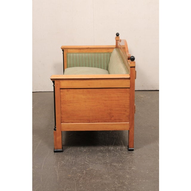 A Swedish Empire Revival birch wood sofa from the mid 19th century. This antique sofa from Sweden features a raised back...