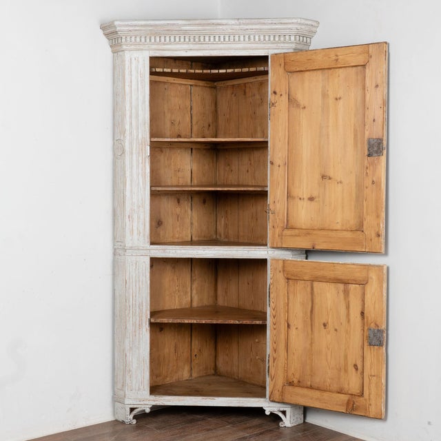 19th century Swedish Gustavian corner cabinet crafted in pine, standing stately just under 7' tall. This cabinet features...