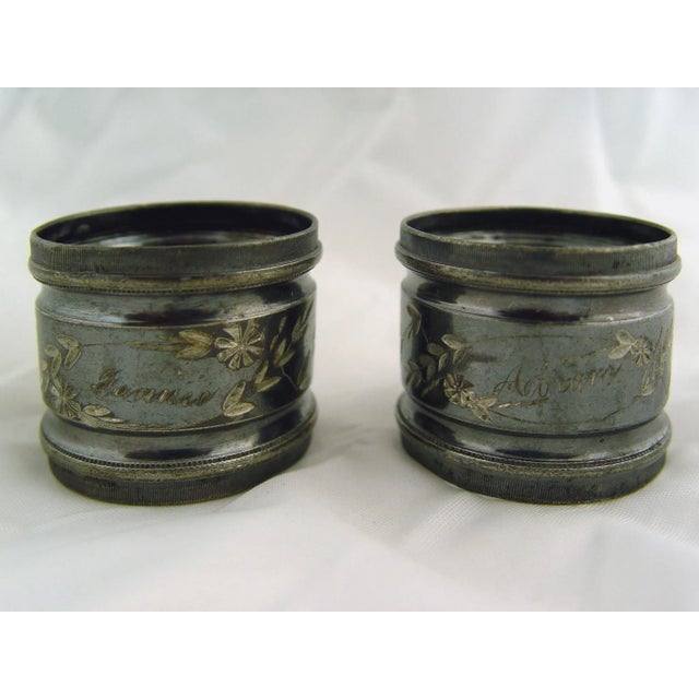 A pair of silver plate napkin rings, engraved floral design with names Fannie and Abram. Produced with a nearly black...