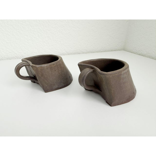 A fun pair of kitsch studio pottery horse hoof coffee mugs crafted of stoneware and glazed in a deep brown. Artist signed...