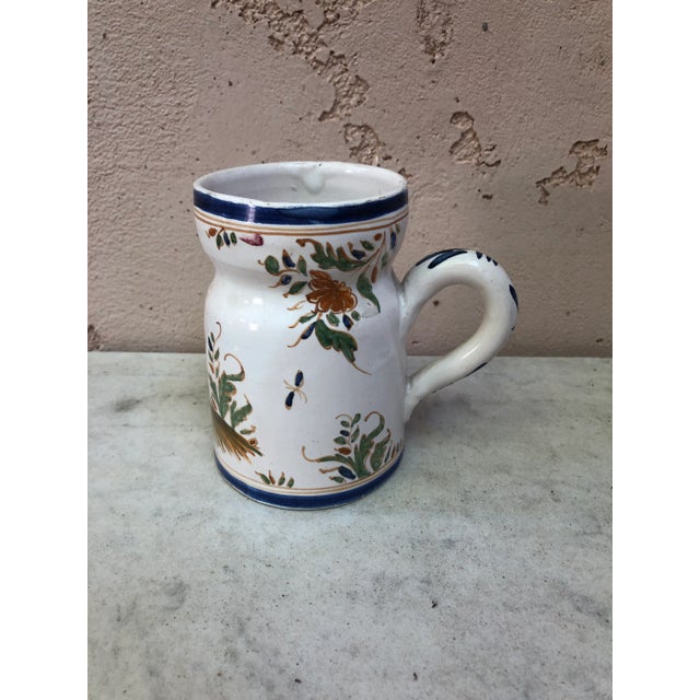 Rustic French Faience Pitcher with floral paintings and man sitting on a fence circa 1920. Moustiers Style.