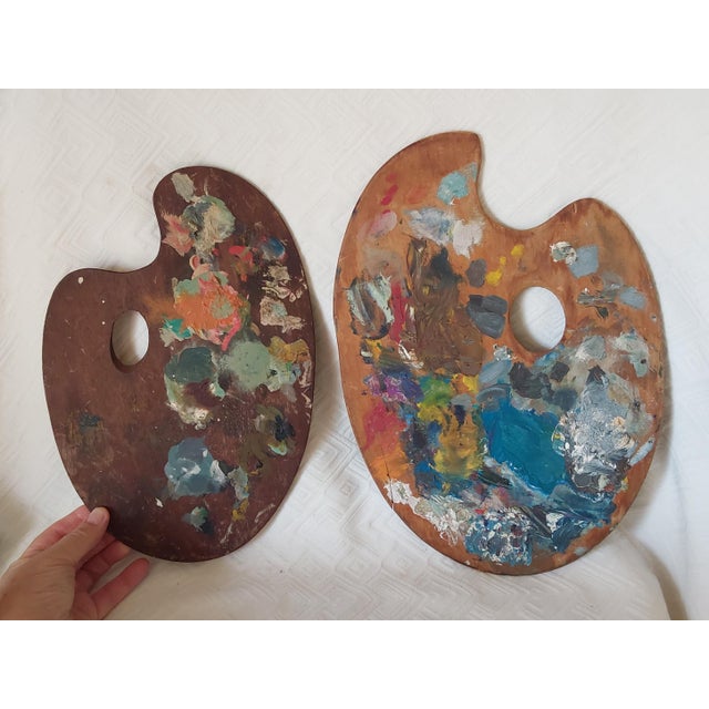 A pair of vintage wood artists palettes. Both have paint on the surface, one is two sided.