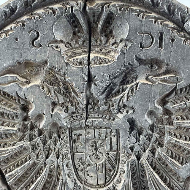 A 1737 round, dark wax butter mold with a negative imprint of the coat of arms of the Austrian imperial family, a crowned...