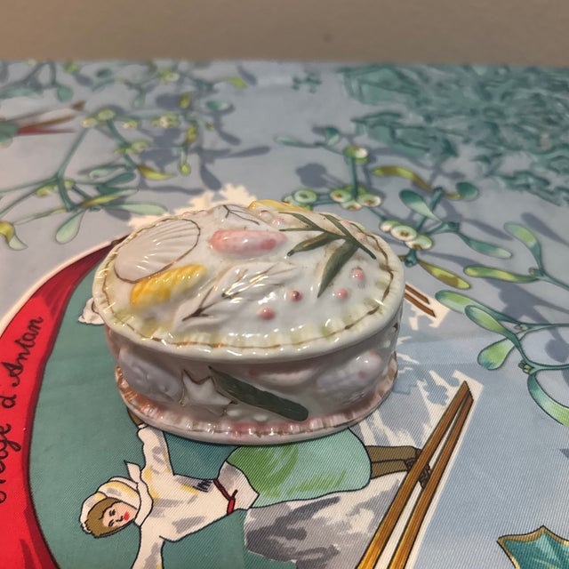 Features a soft, pastel color palette with a light gloss finish. Scalloped edges along the lid and base add a touch of...