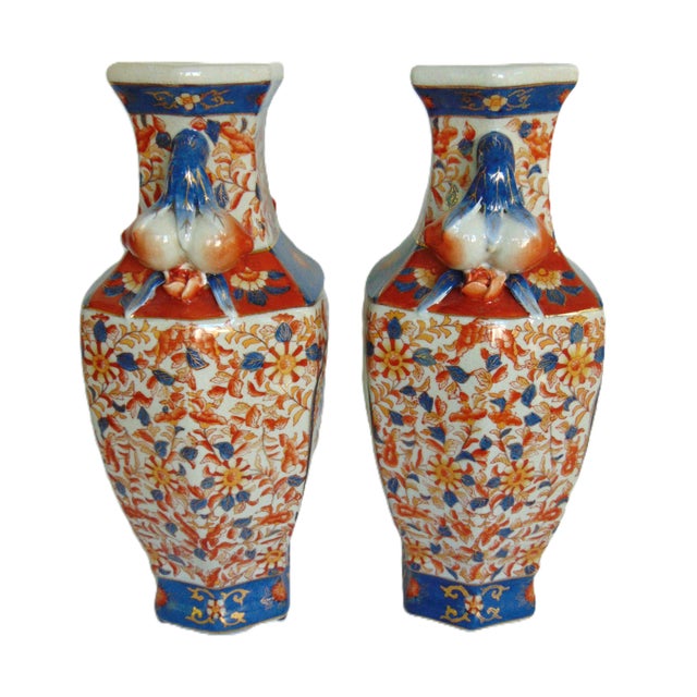 A beautiful pair of hexagonal vases with an Imari design and pomegranate handles on each side. Features red and yellow...
