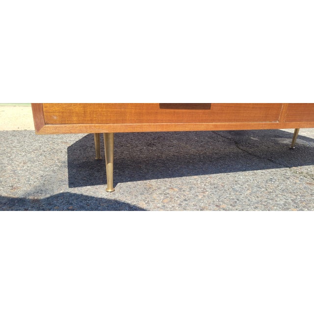 Fine and delicate mid-century modern low chest of drawers with brass handles and Brass legs. Features clean interior....
