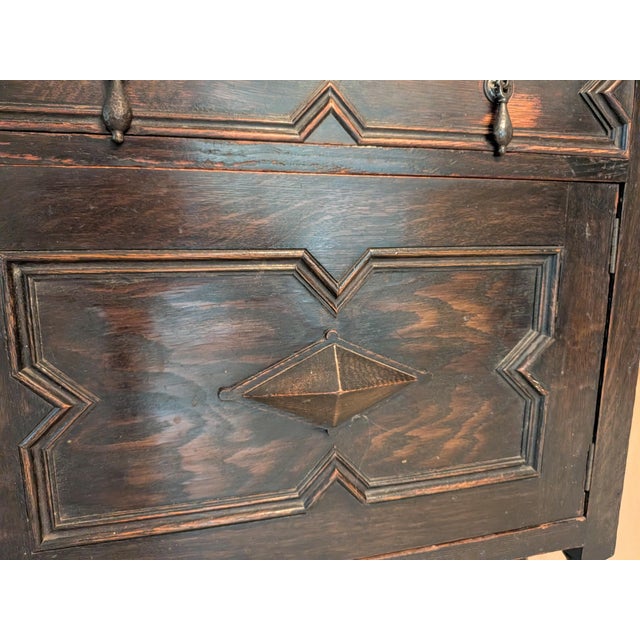This Jacobean sideboard is crafted from rich, dark wood, likely oak, and features intricate geometric carvings with...