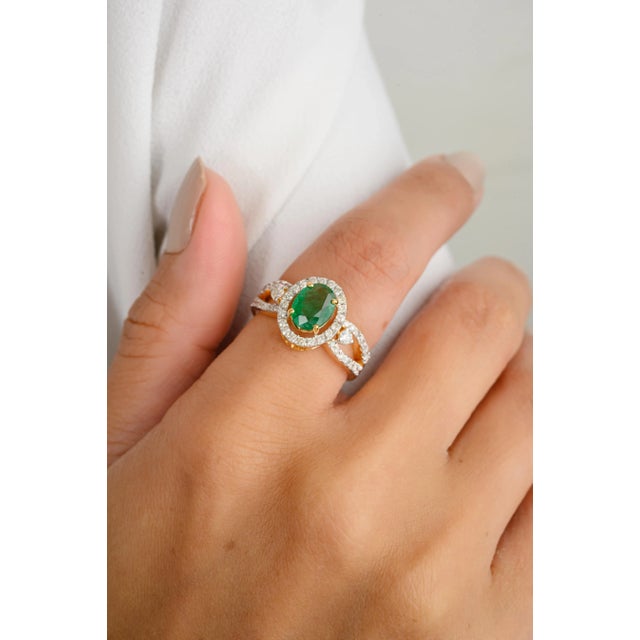 This modern designer ring showcases a stunning natural oval-cut emerald, flanked by brilliant diamonds that enhance its...