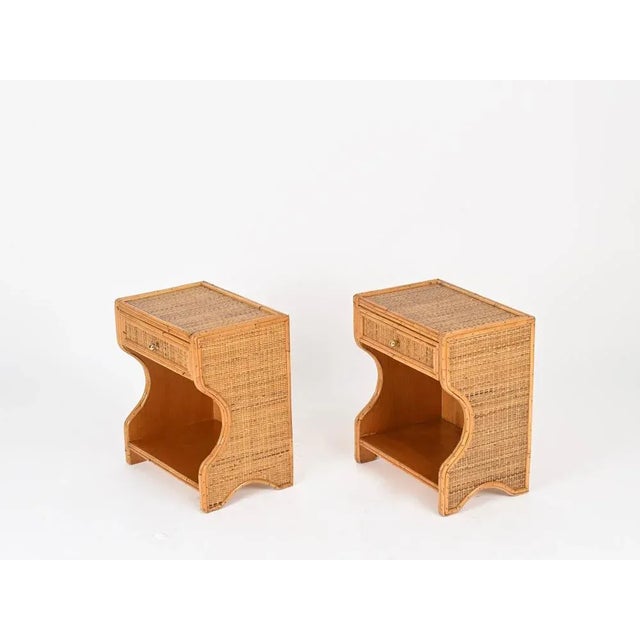 Spectacular pair of Mid-Century nightstands made of curved rattan and woven wicker, completed with solid brass knobs....