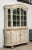 An antique Swedish vitrine in the Gustavian style painted in an ivory color. The top features glazed doors with glazed...