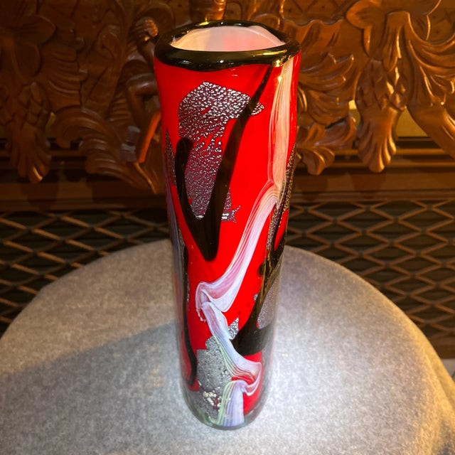 This hand blown Murano Glass Vase is a vibrant red with opaque swirls of blue and green countered by streaks of rich...