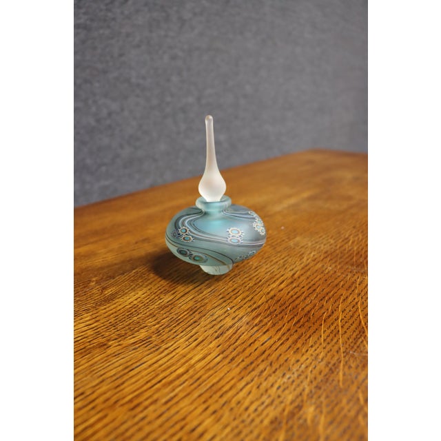 Late 20th-century studio art glass perfume bottle with a rounded, flattened form and elongated frosted glass stopper. The...