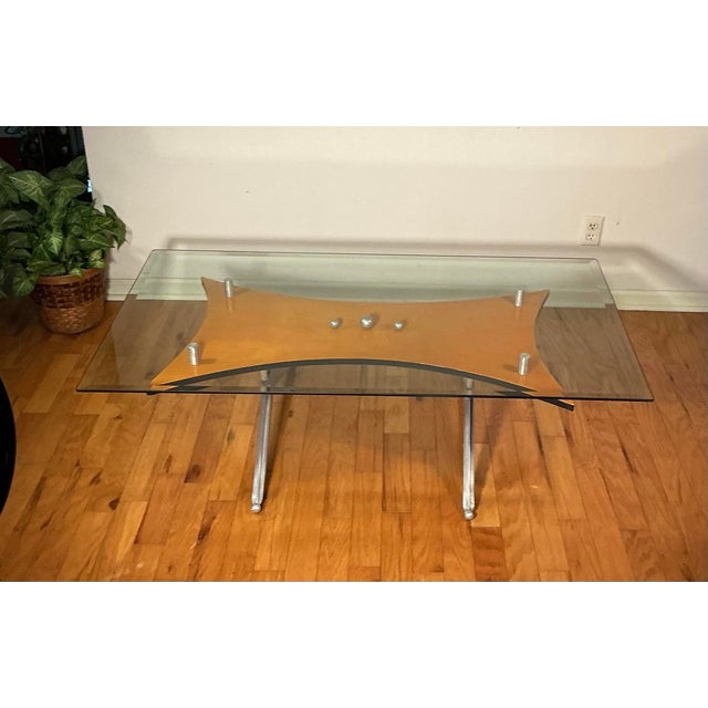 Stylish formed coffee table. This table consisting of a solid cast aluminum base, birch veneer with floating glass top...