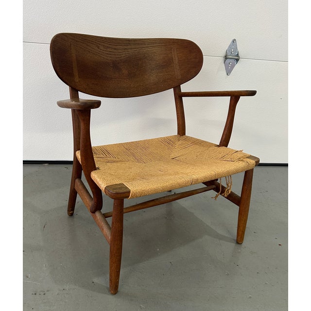 Pair of mid century project CH22 lounge chairs by Hans Wegner for Carl Hansen. Each chair is in need of new paper cord...